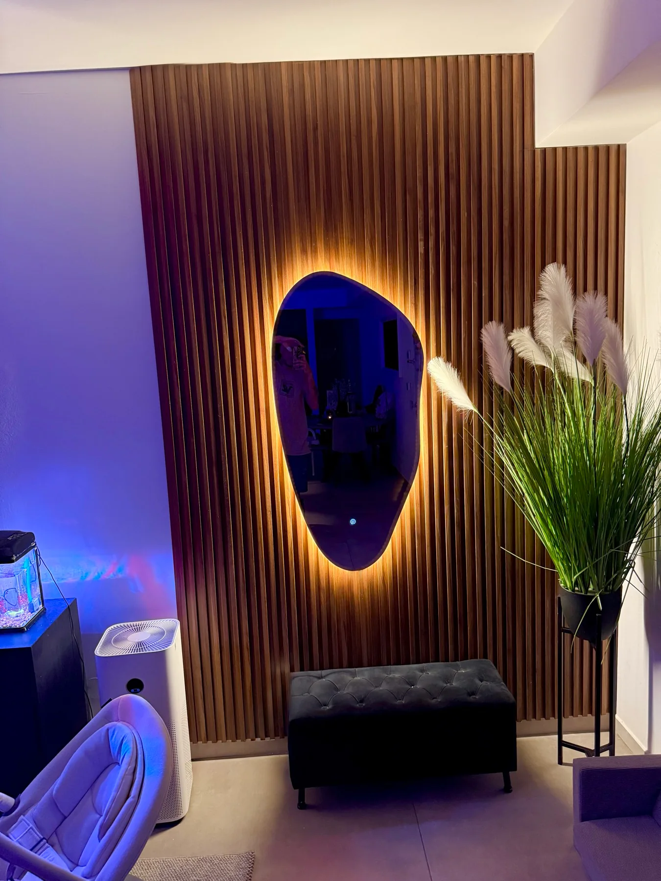 מראת LED touch מאירה הילה על קיר סרגלים פולימריים בגוון אגוז, בערב